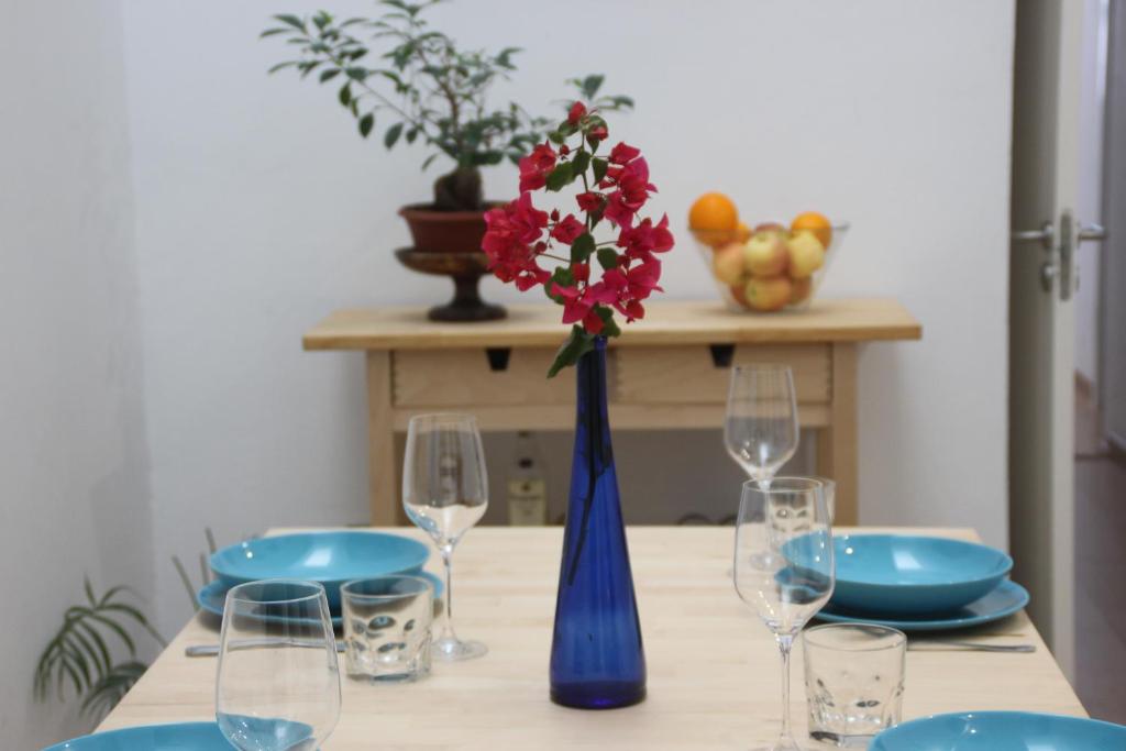 大加那利岛拉斯帕尔马斯Celia House的一张带红色花卉和玻璃杯的蓝色花瓶桌子