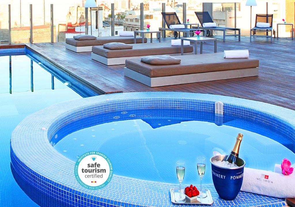 巴塞罗那Axel Hotel Barcelona - Adults Only的游泳池提供一瓶香槟和酒杯