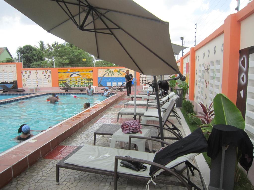 达累斯萨拉姆Jakicha Motel的一个带一排椅子和遮阳伞的游泳池