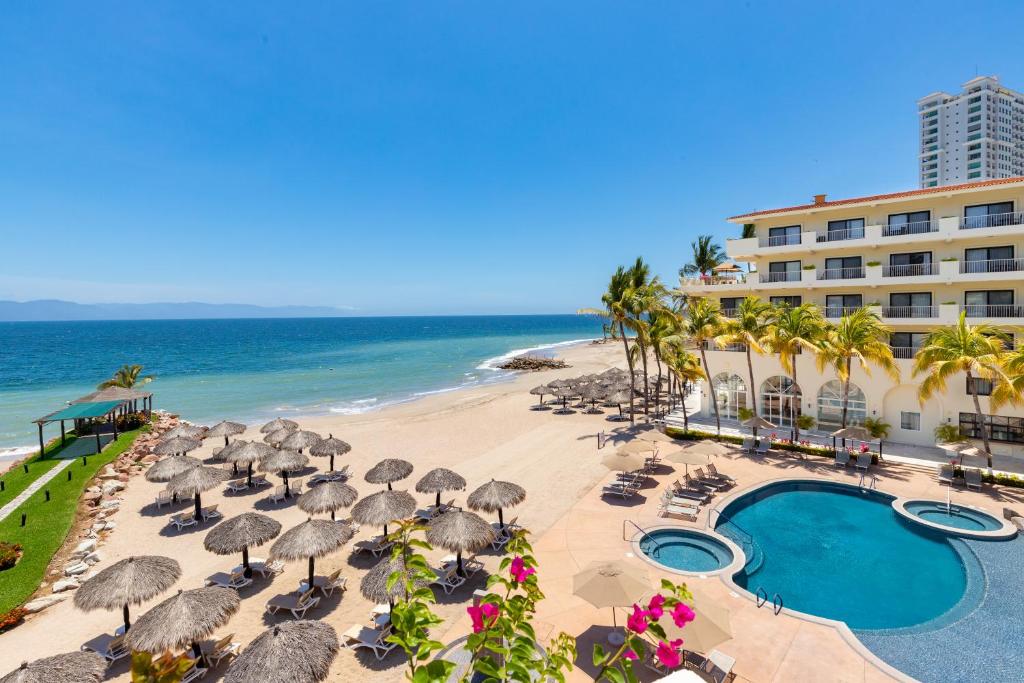 巴亚尔塔港巴亚尔塔港德尔帕尔马海滩别墅度假水疗酒店的一个带遮阳伞和椅子的海滩和一家酒店
