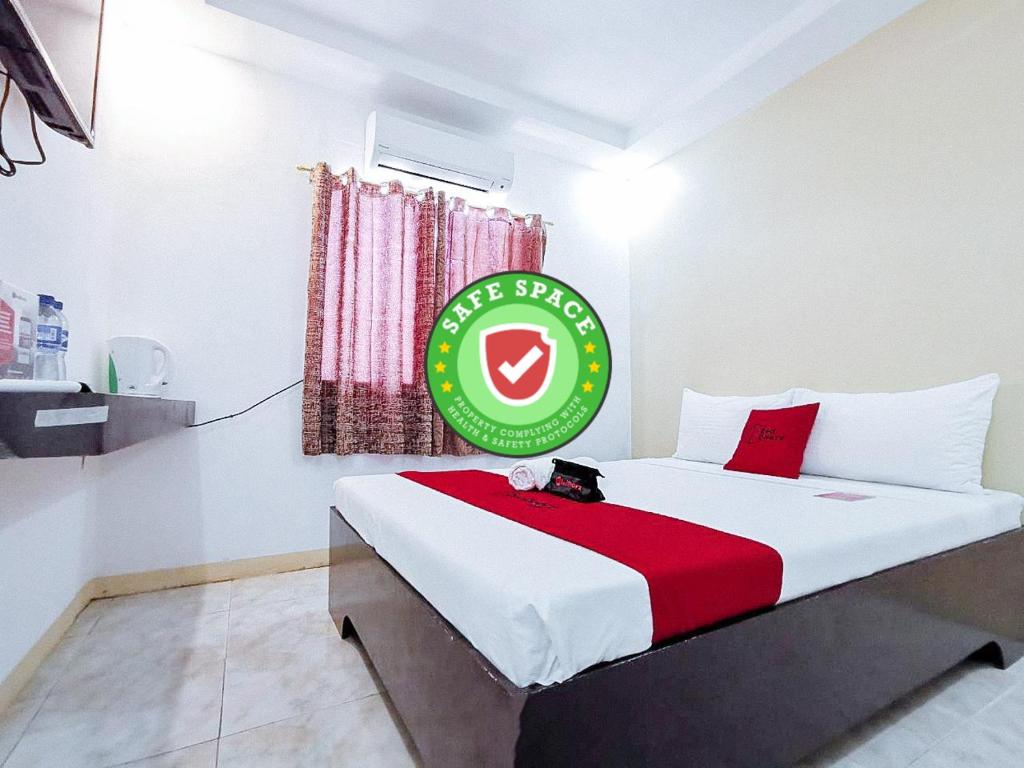 桑托斯将军城RedDoorz near Notre Dame of Dadiangas University的一间卧室,配有一张带标志的床