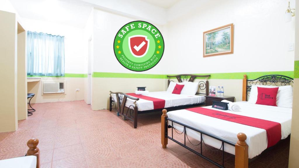 卡兰巴RedDoorz Praferosa Resort Hotel Calamba的酒店客房设有三张床,墙上有标志