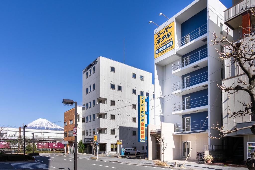 富士市Super Hotel JR Fujiekimae Kinenkan的白色的建筑,旁边标有标志