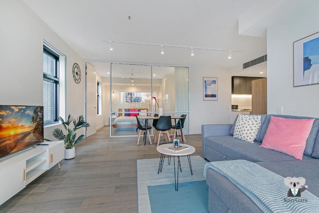 悉尼KOZYGURU WOLLI CREEK KOZY 1 BED APT SYDNEY AIRPORT & SYDNEY CBD NWC020的客厅配有蓝色的沙发和桌子
