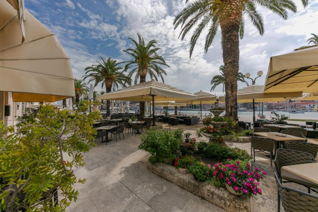 特罗吉尔康克狄亚酒店的一个带桌子和遮阳伞及棕榈树的庭院