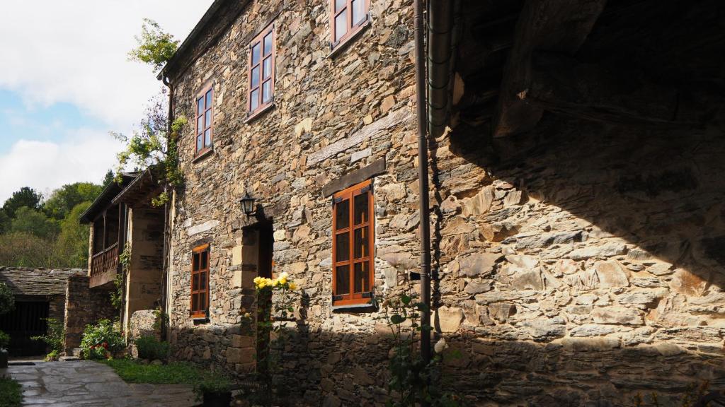 San Martín de OscosCasa del forno的一座古老的石头建筑,拥有橙色的窗户