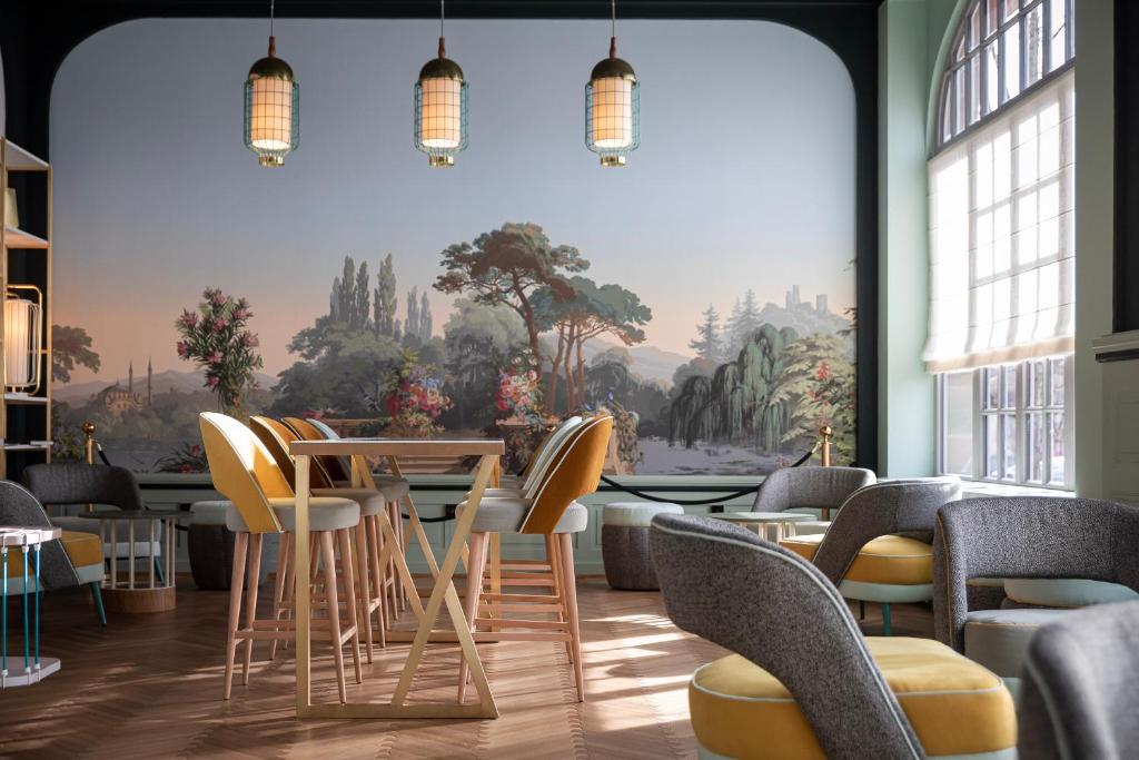 科尔马Grand Hôtel Bristol的一间带椅子和桌子的餐厅以及壁画