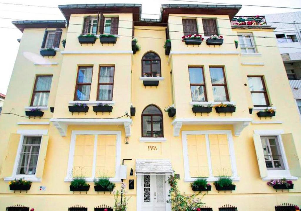 伊兹密尔Historical Ottoman Manor的黄色的建筑,上面有盆栽植物