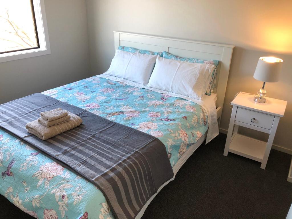 汉密尔顿Central Stadium Apartments的一间卧室配有一张床和一个带床罩的床头柜。