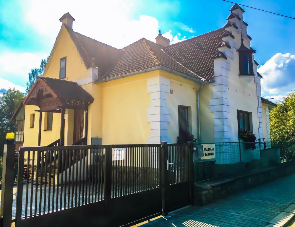 普拉哈季采Apartmán v Zahradní的黄色和白色的房子,有黑色的围栏
