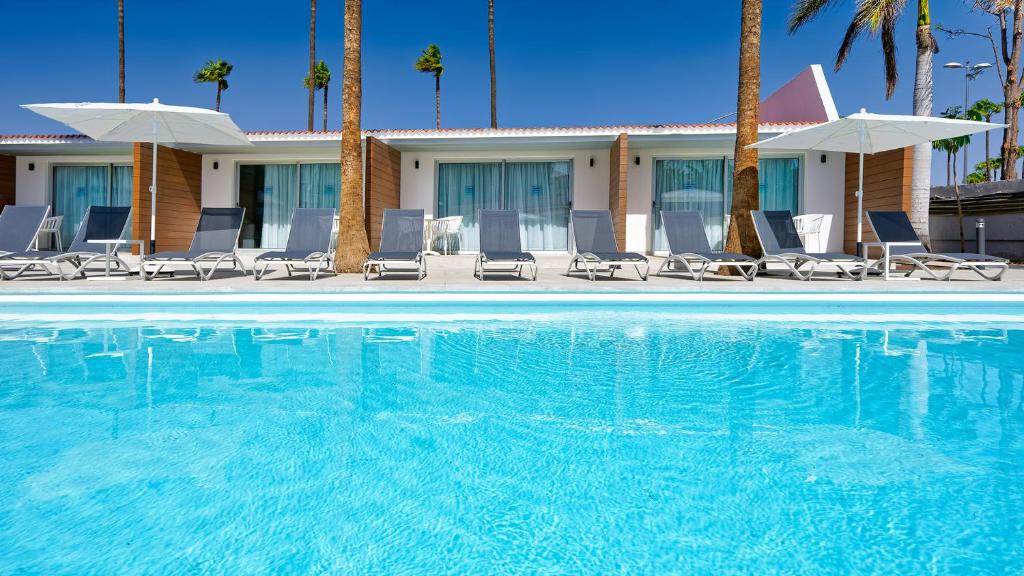 英格兰海滩Sanom Beach Resort Only Adults的一座游泳池,里面摆放着椅子和棕榈树
