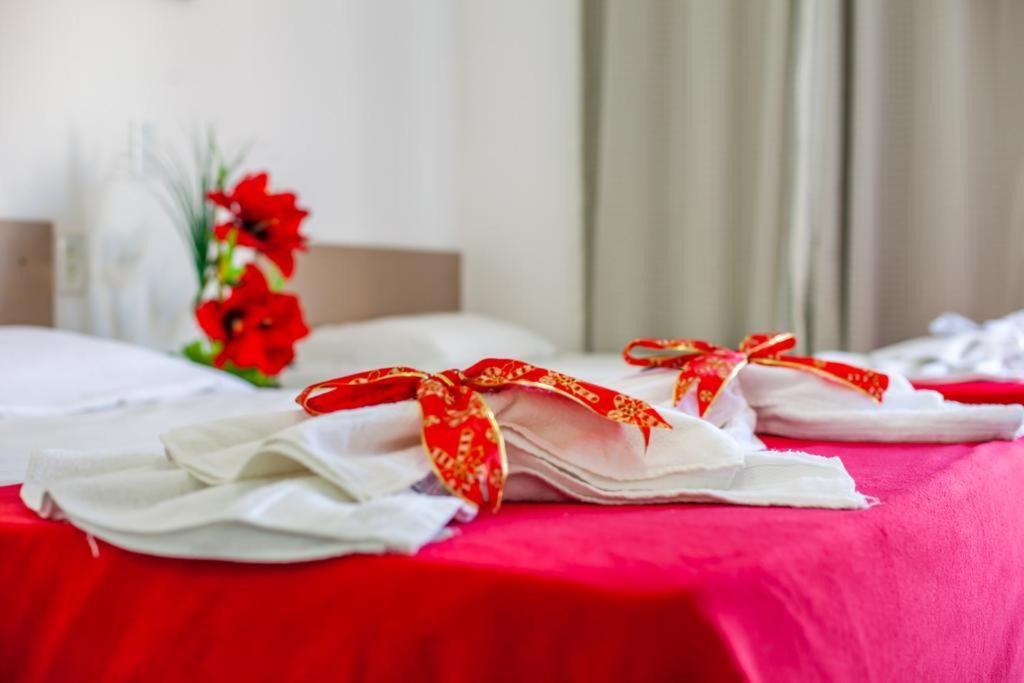 福塔莱萨Luxury Flats Ambiente Cristão的一组白色毛巾,床上有红色的弓