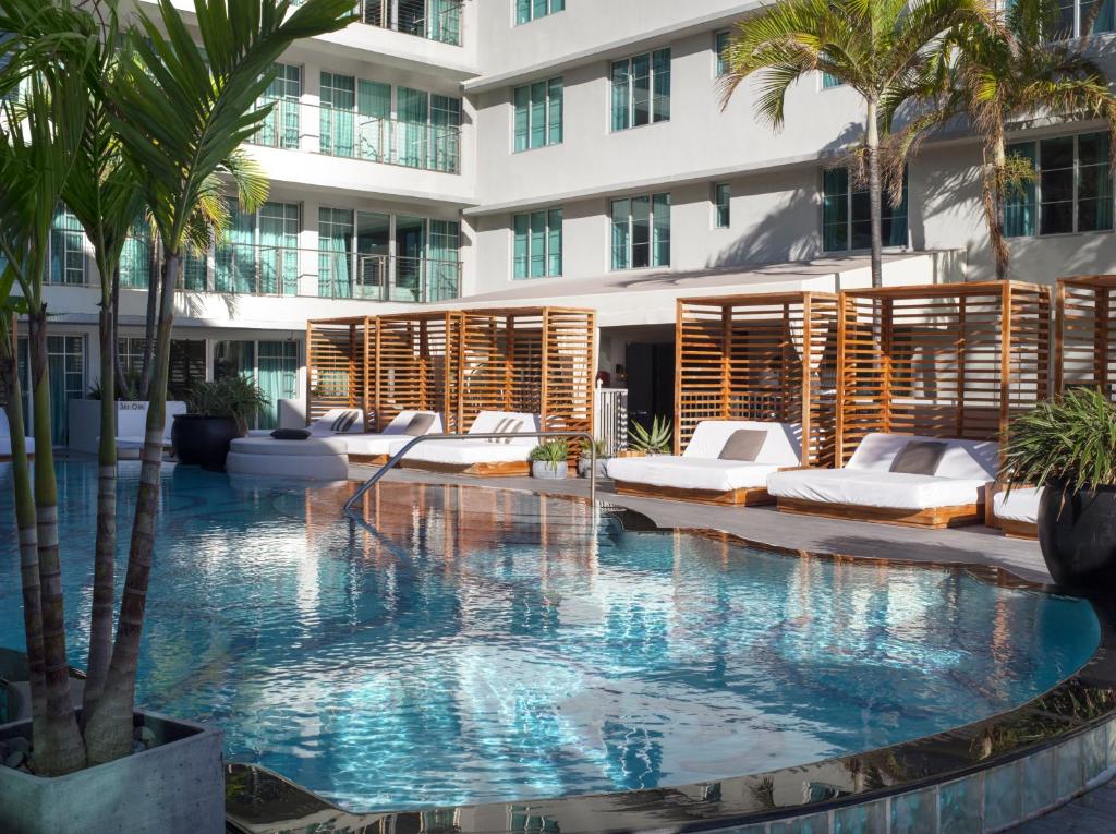 迈阿密海滩维克多南海滩酒店的酒店游泳池设有躺椅和棕榈树