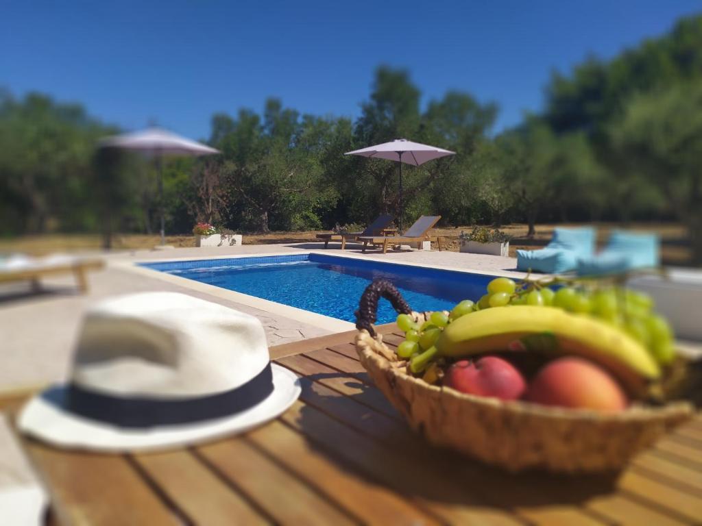 瓦西里科斯Loggos Summer House的游泳池畔桌子上的一篮水果