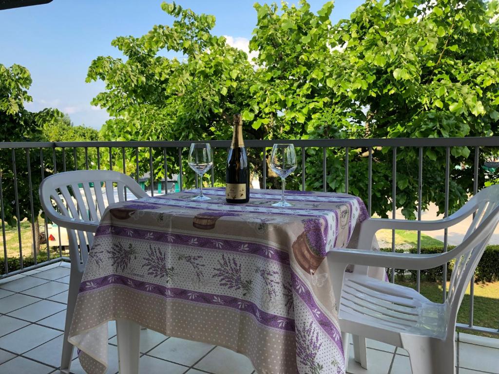 西尔米奥奈Ohana Apartments Camping Tiglio的一张桌子上摆放着一瓶葡萄酒,还有两把椅子
