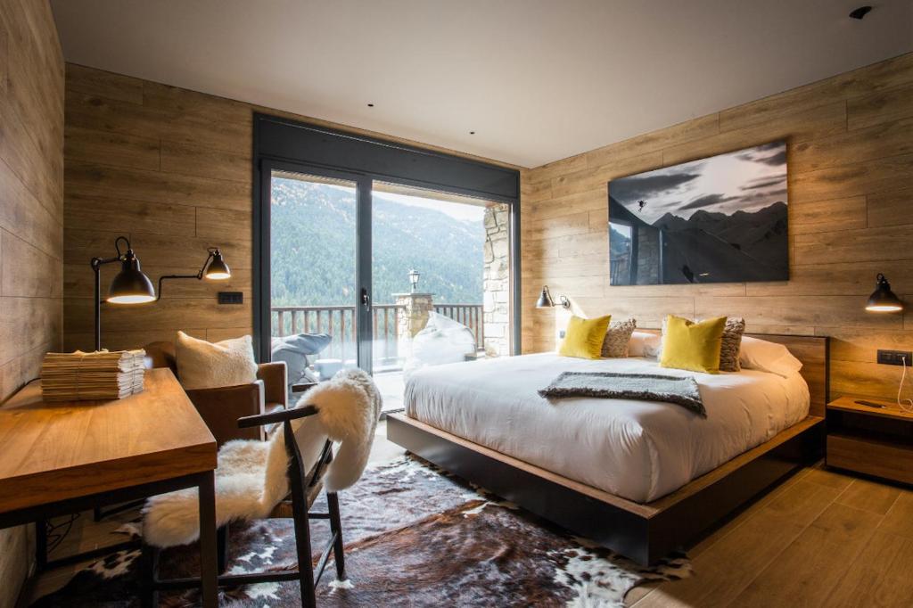 索尔德乌Luxury Ski Chalet Andorra的一间卧室配有一张大床、一张书桌和一个窗户。