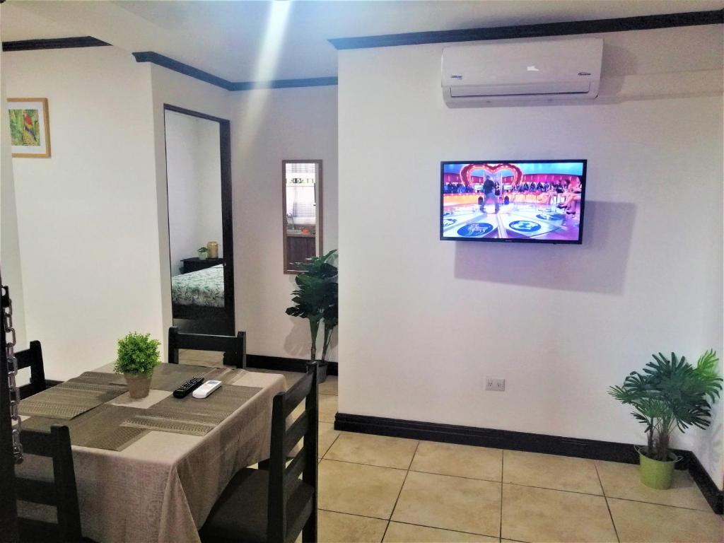 阿拉胡埃拉Kubo Apartment Private 2 Bedrooms 5 mins SJO Airport with AC的一间设有桌子和墙上电视的用餐室
