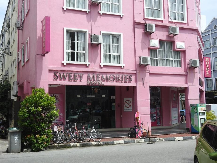 马六甲Sweet Memories Hotel的一座粉红色的建筑,前面停放着自行车