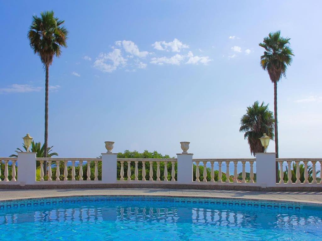 苏昂博Casa de la Belvedere - Wonderful sea views - Elegant terrace area - Great for families的一个带围栏和棕榈树的游泳池