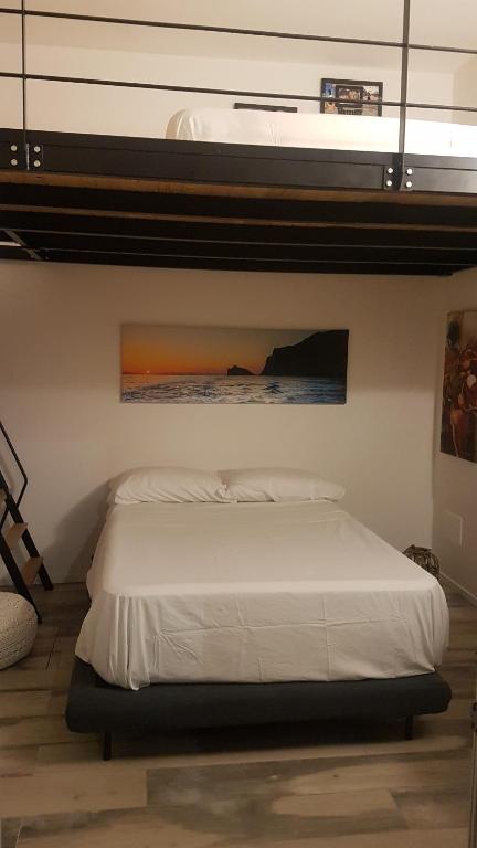 马里迪莫La casa a due passi dal mare的卧室配有一张白色床,墙上挂有绘画作品