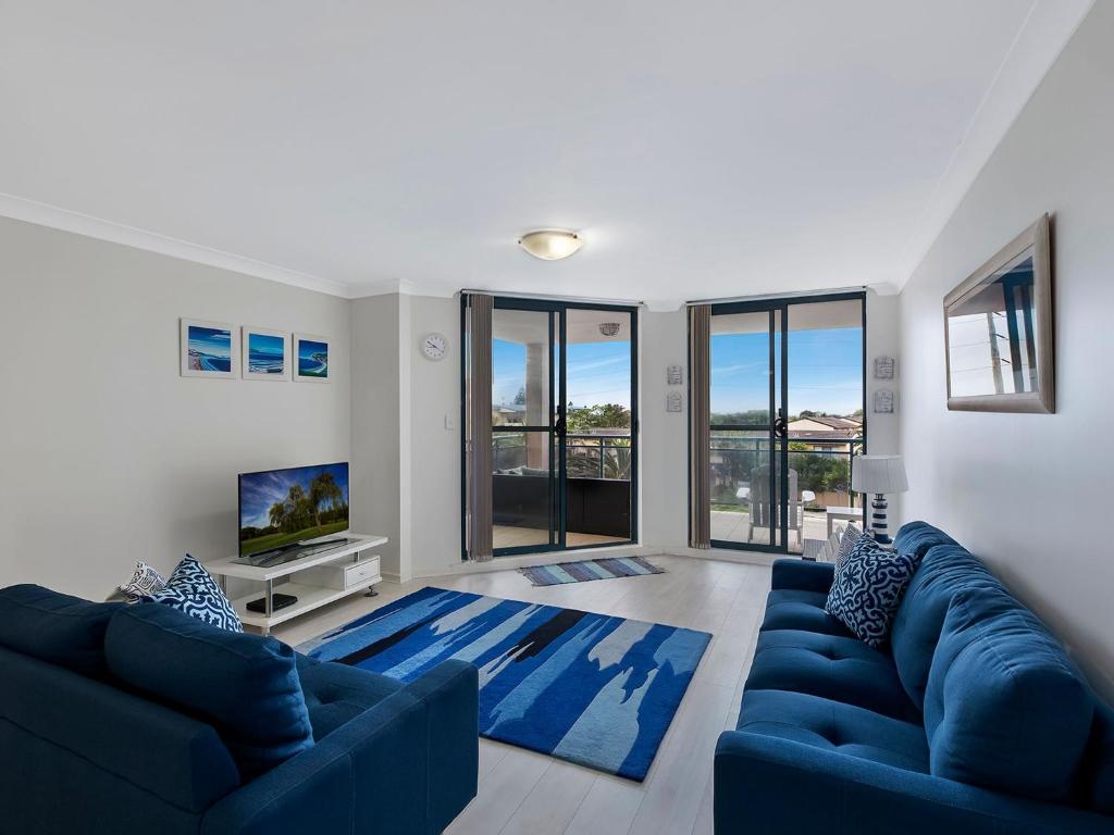 安特兰斯双岸67公寓的客厅配有蓝色的沙发和蓝色的地毯。