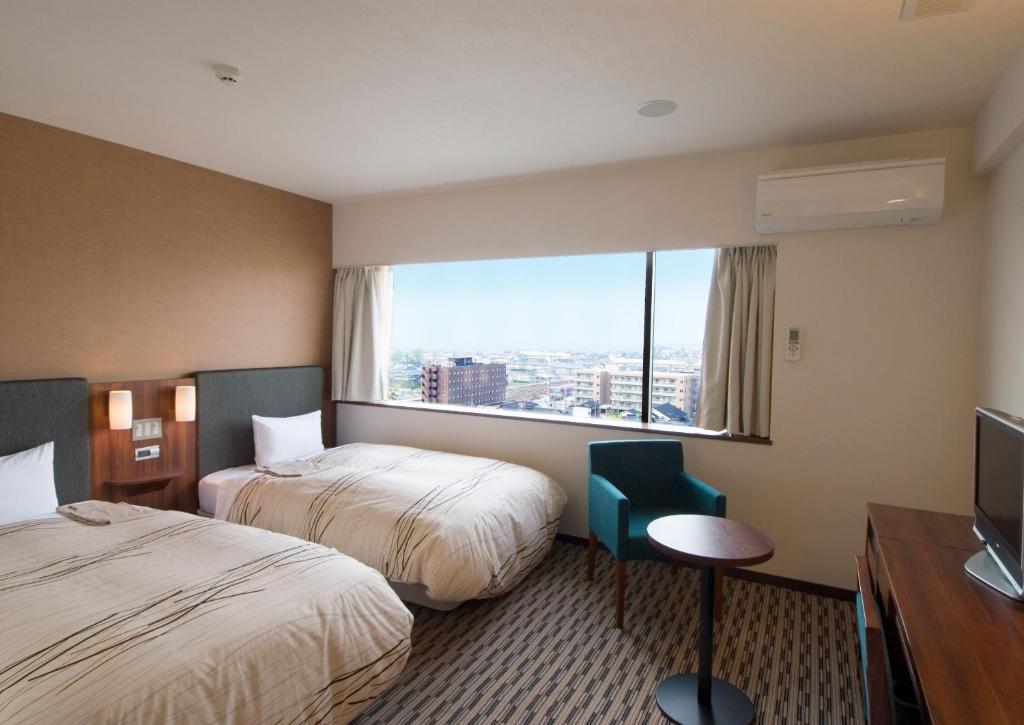 鱼津鱼津门通站前酒店的酒店客房设有两张床和窗户。