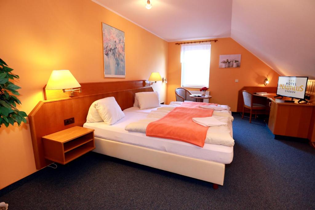 Chodovhotel Nautilus的酒店客房设有一张大床和一张书桌。