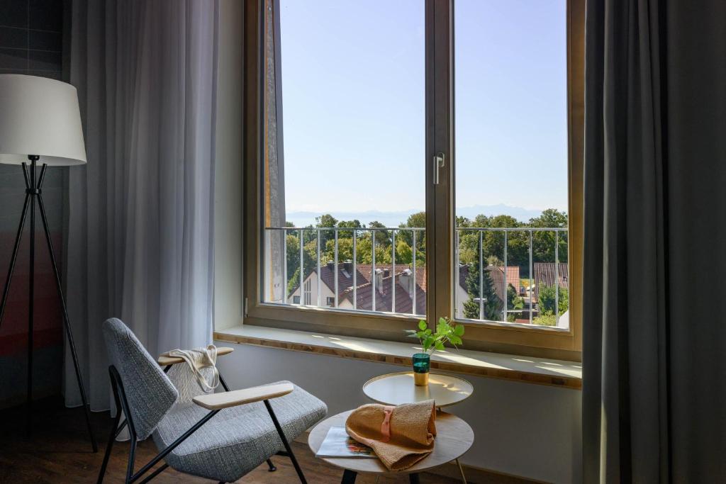 腓特烈港Hotel Maier的客房设有带2把椅子和1张桌子的大窗户。