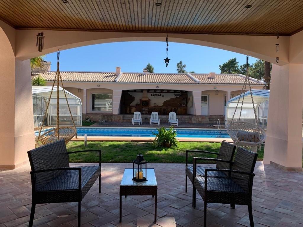 克洛伊奥斯Moradia Pinhal da Telha的一个带桌椅的庭院和一个游泳池