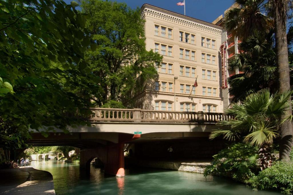 圣安东尼奥圣安东尼奥河滨德鲁利套房酒店的一座建筑物前的河上桥梁