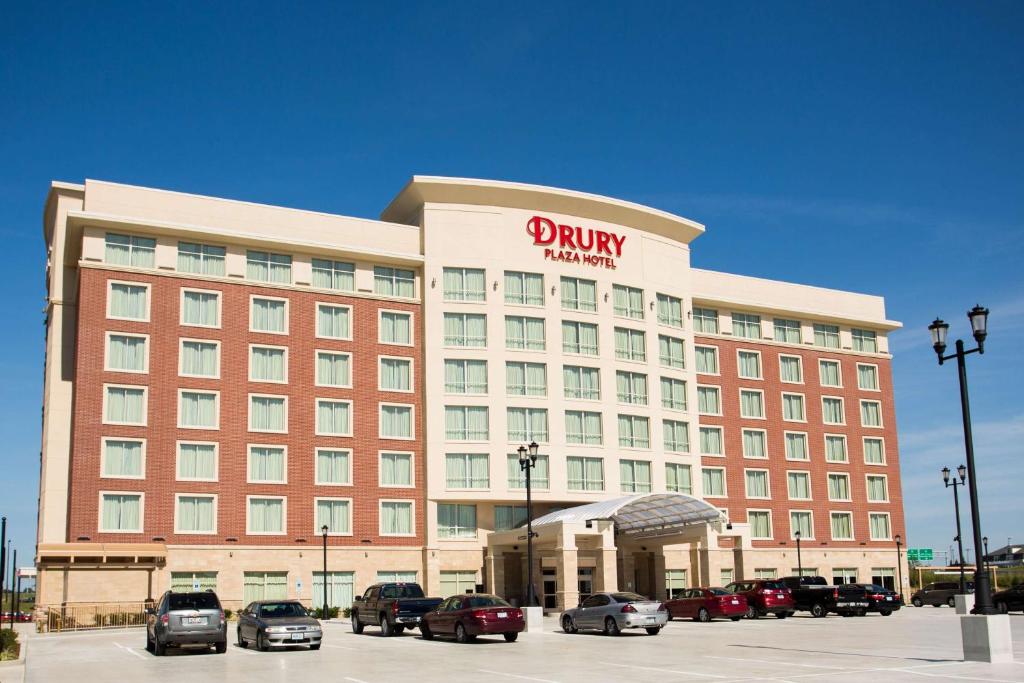 圣查尔斯Drury Plaza Hotel St. Louis St. Charles的停车场内停放汽车的酒店大楼