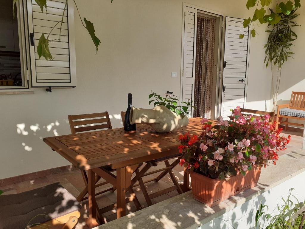 奥罗塞伊Villa Pusortu的一张木桌,上面放着一瓶葡萄酒和鲜花