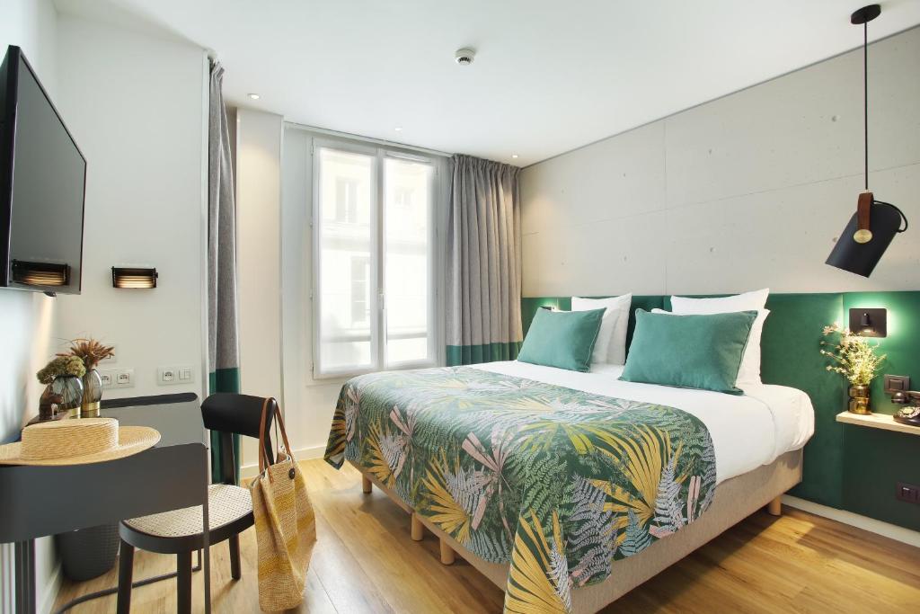 巴黎Le Basile Hôtel的配有一张床、一张桌子和一张桌子的酒店客房