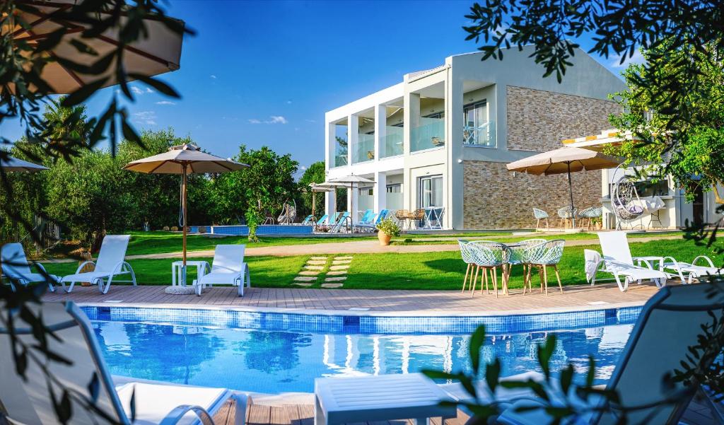 普雷韦扎Alonaki Resort的一座房子,设有一座带椅子和遮阳伞的游泳池