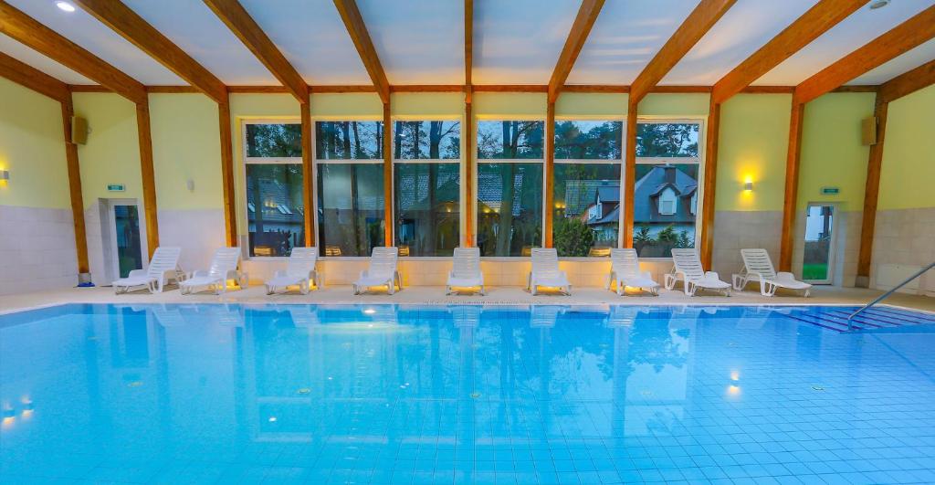 米泽德沃兹Millennium Health Resort & Spa的一个带白色椅子的游泳池和一间大房间
