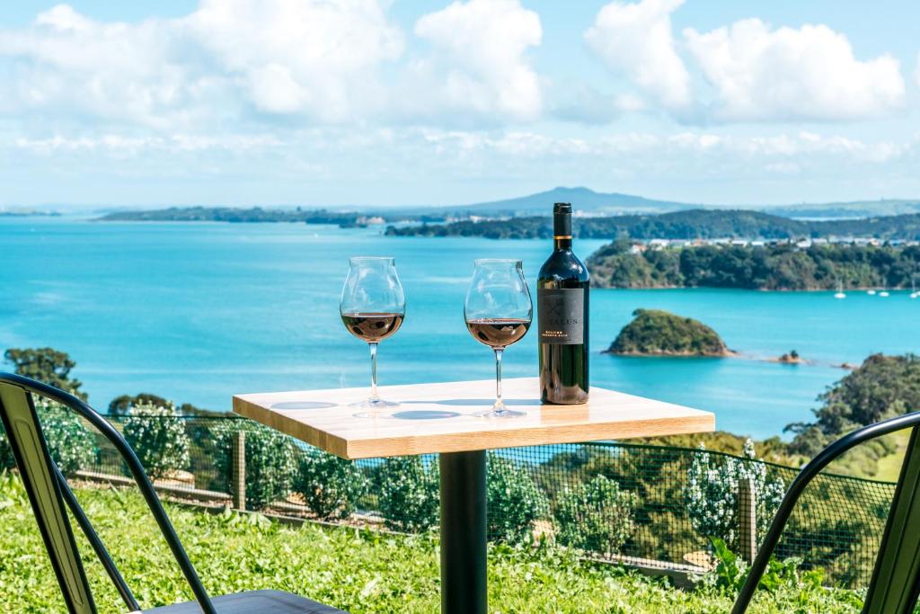 OmihaThe Apartment - Sea Views at Te Whau Point by Waiheke Unlimited的桌子上放有一瓶葡萄酒和两杯酒