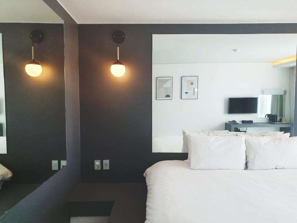 济州市Pampas Hotel Jeju的一间卧室配有带白色枕头和2盏灯的床。