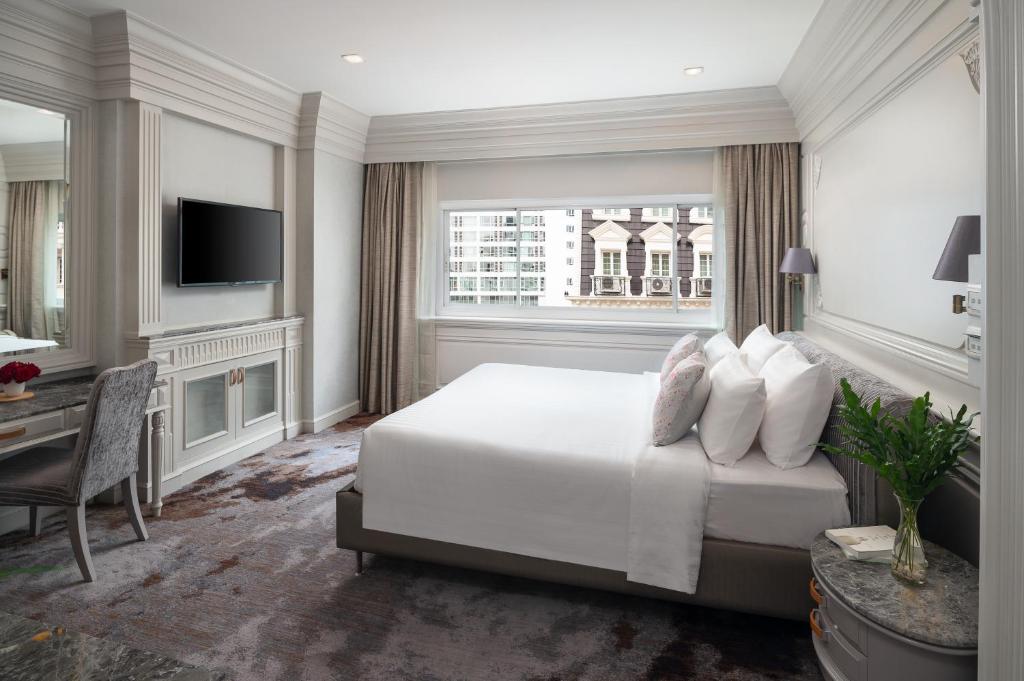 曼谷Kingston Suites Bangkok的一间卧室配有一张床、一张书桌和一台电视