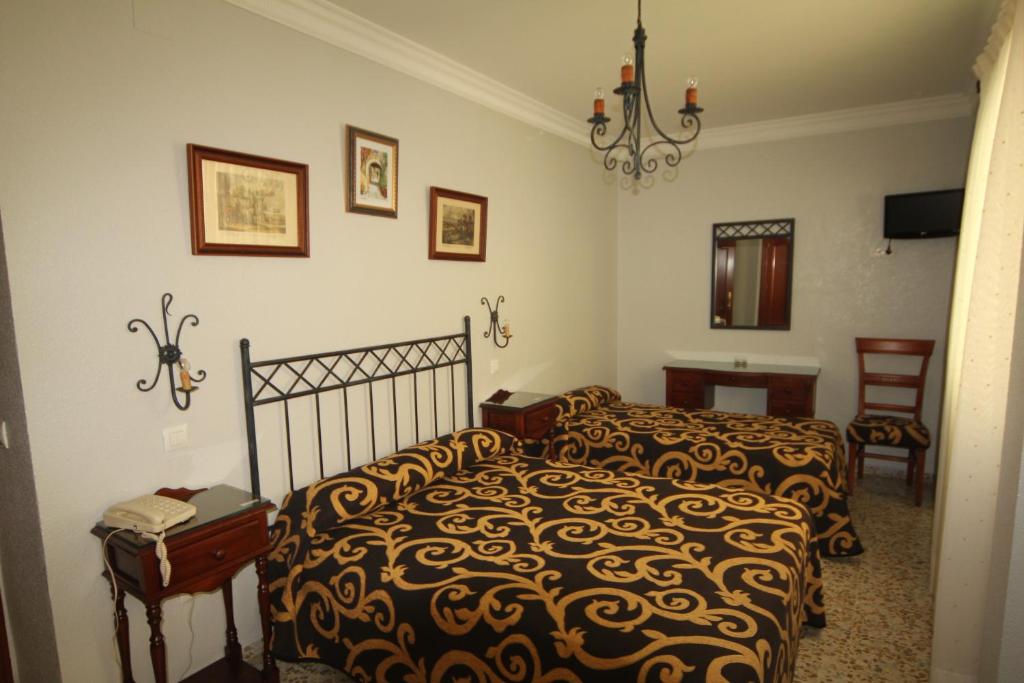 塞维利亚罗马旅馆的一间卧室配有一张床和一个吊灯