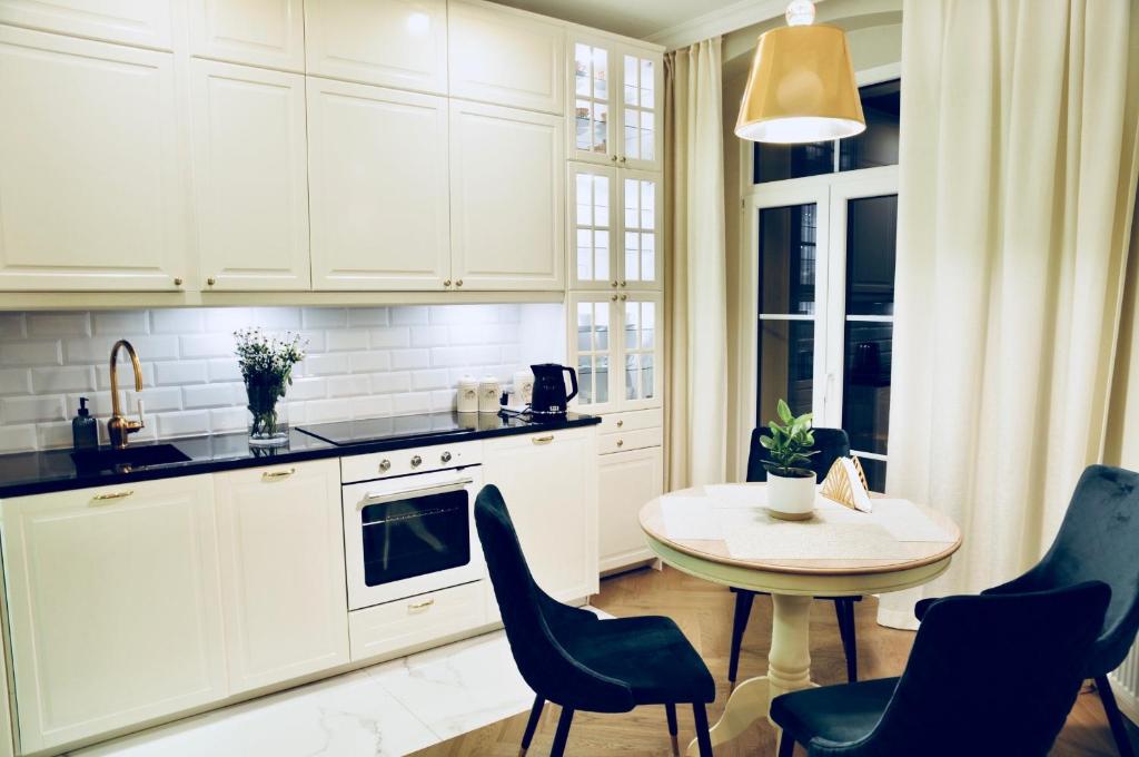 罗兹GOLD APARTMENT Piotrkowska 37的厨房配有白色橱柜和桌椅