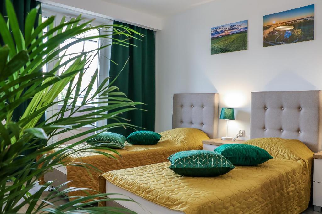 比亚韦斯托克Apartament Podlaskidron的客房内的两张床和绿色枕头