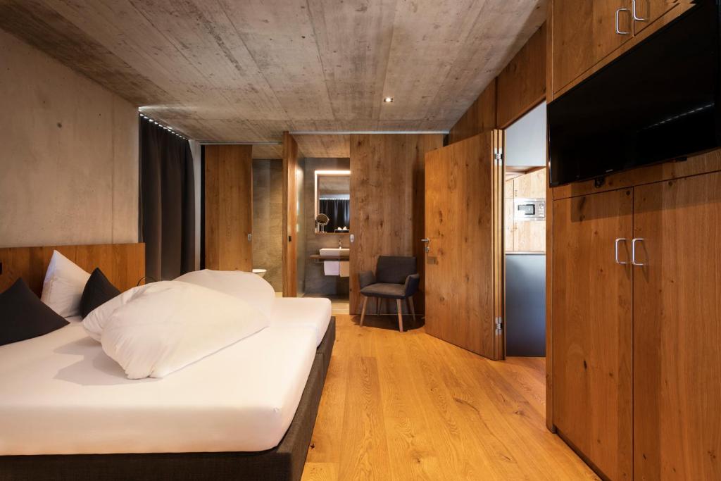 圣安东阿尔贝格Apart6580的一间卧室配有一张床、木制橱柜和一台电视。