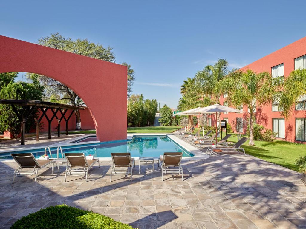 阿瓜斯卡连特斯阿瓜斯卡连特斯嘉年华酒店的一座带椅子的游泳池以及一座建筑