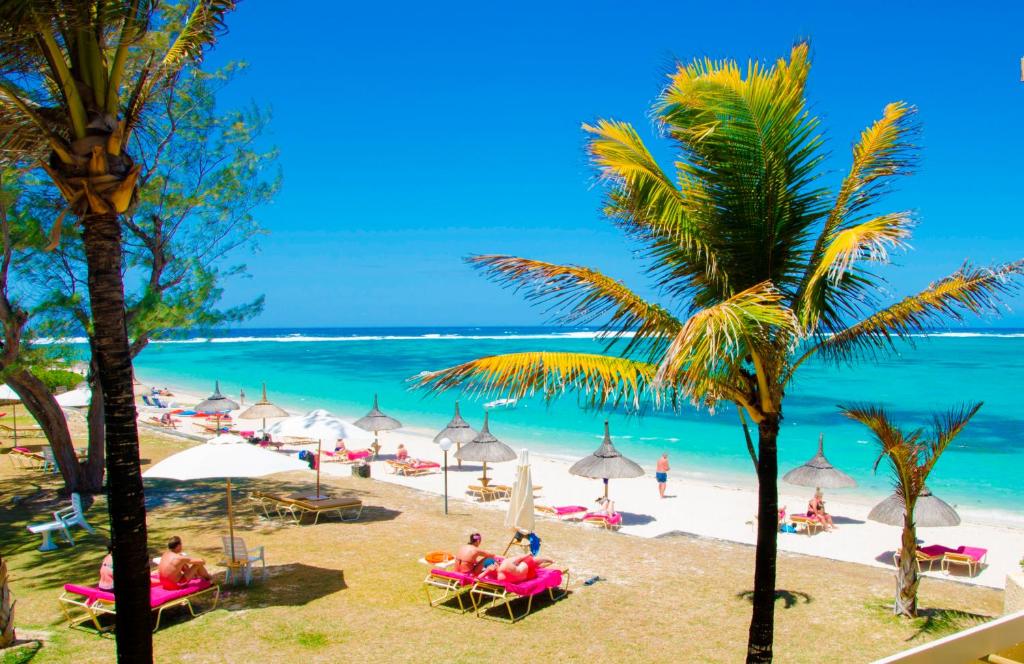 托舵道斯银色海滩酒店的海滩上有人坐在椅子和遮阳伞上