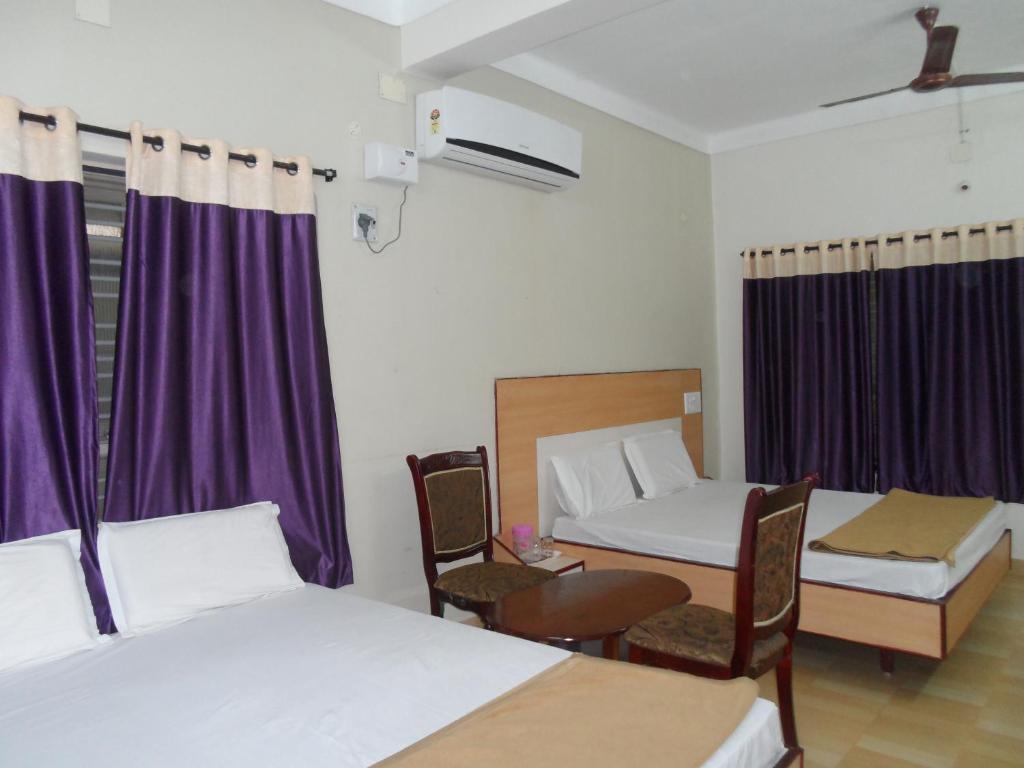 蒂鲁帕蒂Hotel Pasuparthy Residency的一间设有两张床和一张桌子及椅子的房间