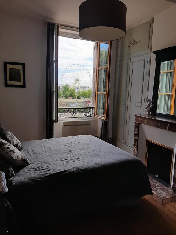欧塞尔Et au pied coule une rivière, situation et vue idéales的一间卧室配有一张床和一个带摩天轮的窗户