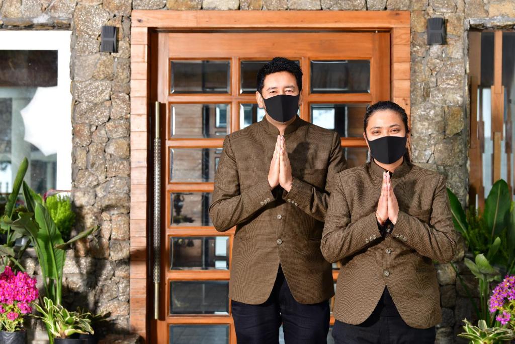 KurseongAllita Hotel & Resorts的戴面具站在门前的男人和女人