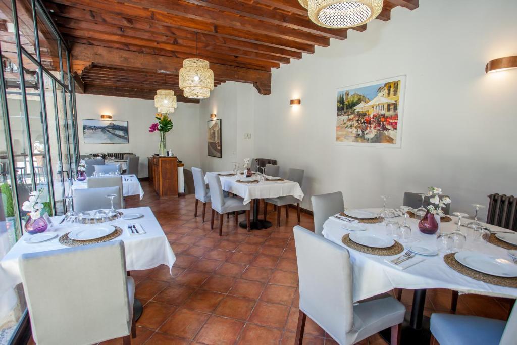 UclésHotel Casa Palacio Uclés的一间设有白色桌椅的用餐室