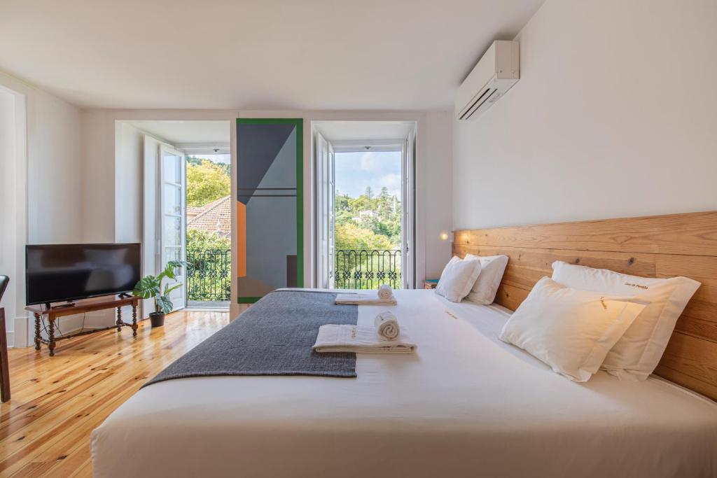 辛特拉卡萨达潘多酒店的卧室配有一张白色大床和电视。