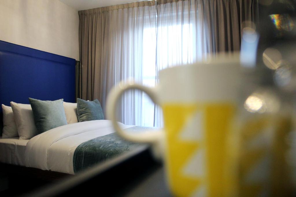 伦敦CG Kensington的酒店客房带一张床和一杯啤酒